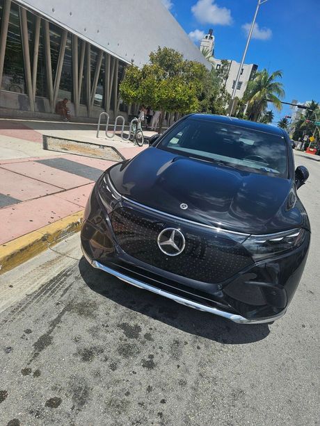 A black mercedes benz is parked on the side of the road.