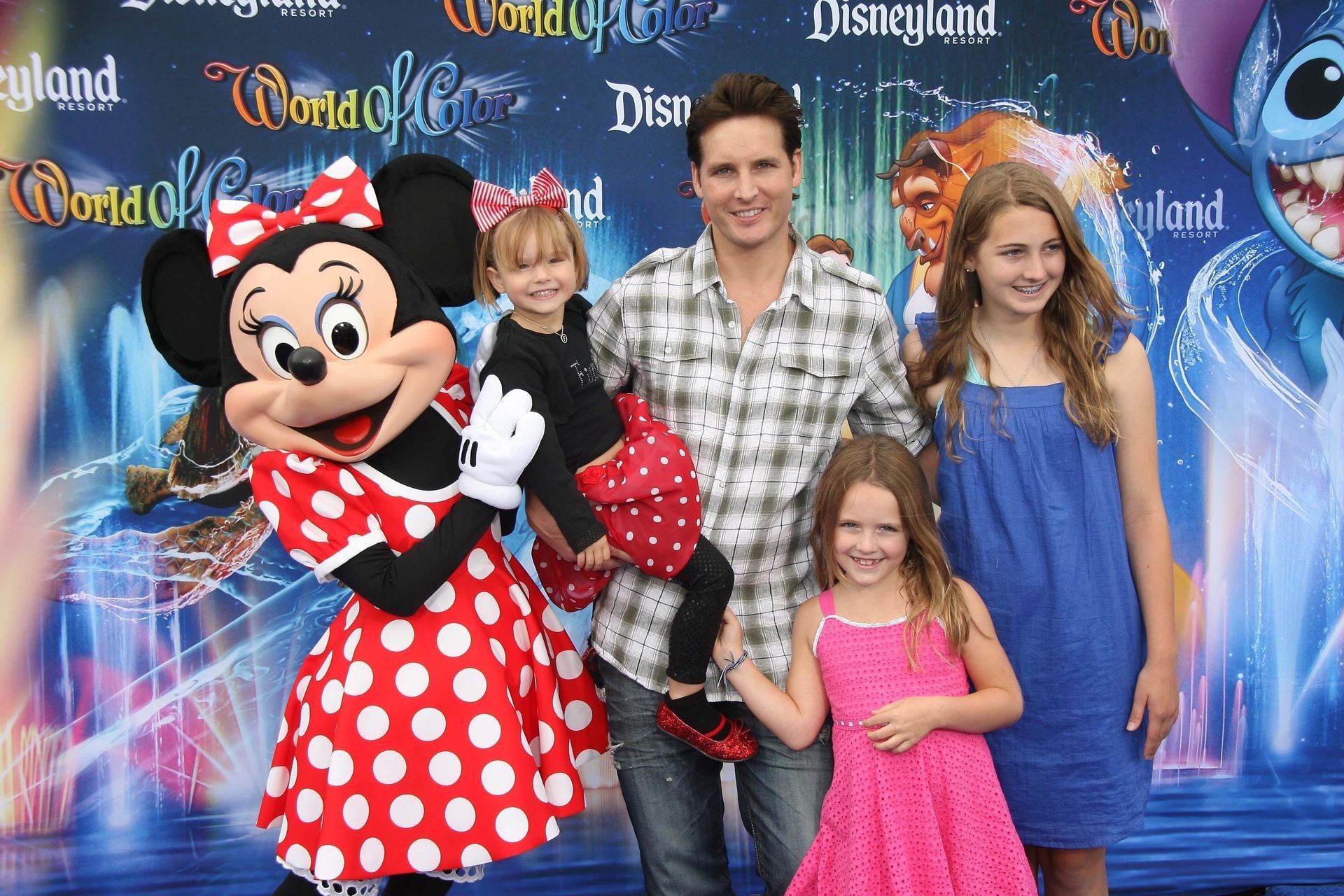 A man and three children pose for a picture with minnie mouse