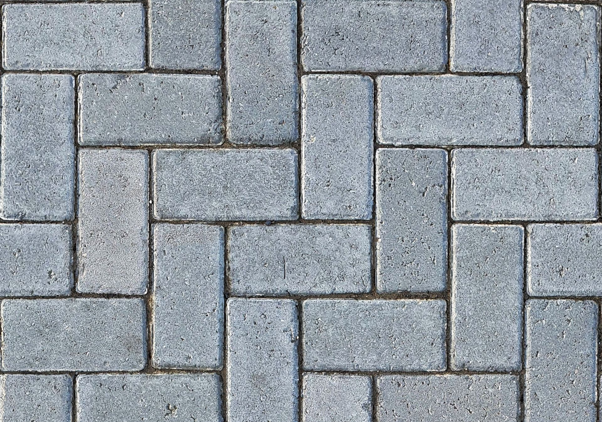 Gray interlocking brick pavers with a repeating woven pattern and thin dark seams
