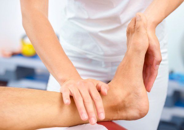 Physical therapist massaging a patient’s ankle and foot on a treatment table