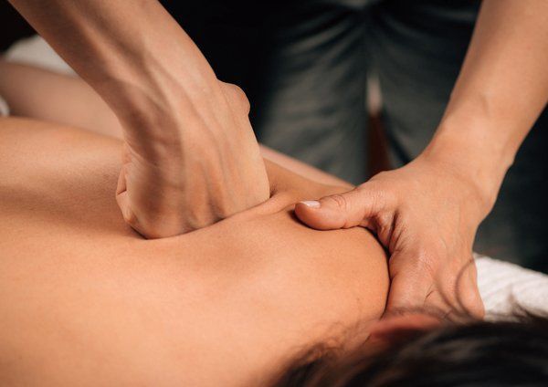 Massage therapist kneading a client’s back with hands during a massage session