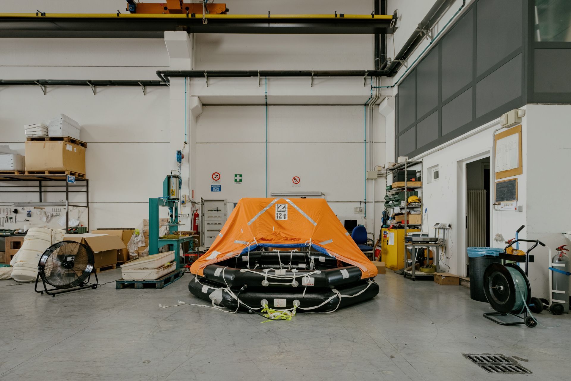Orange race car in a workshop garage, surrounded by tools and equipment on a concrete floor.