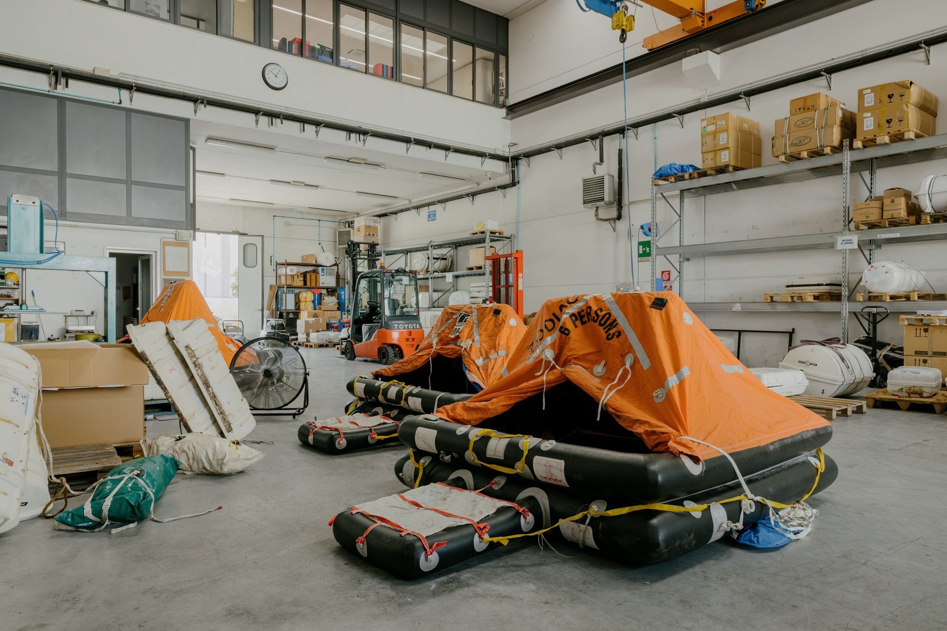 Orange jet skis in a warehouse workshop, surrounded by tools, boxes, and equipment.