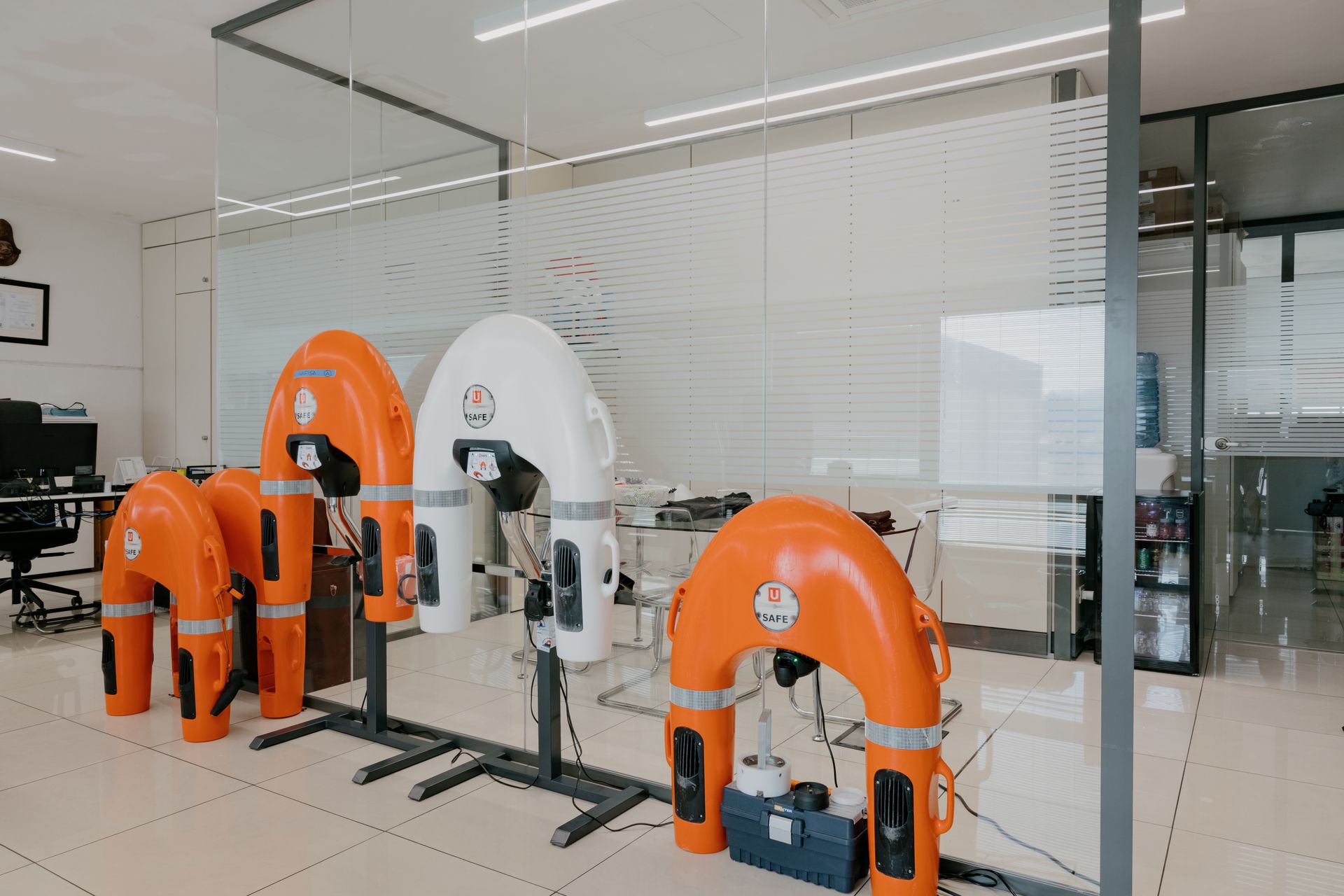 Orange industrial robot arms in a glass-walled lab or factory workspace