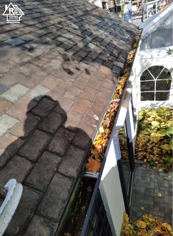 A gutter filled with leaves on the side of a house