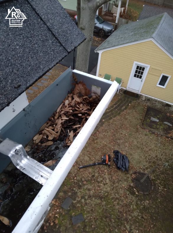 A gutter filled with leaves next to a house
