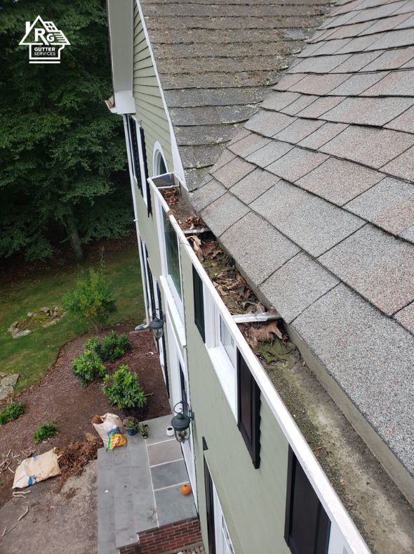 An aerial view of a house with a gutter filled with leaves.
