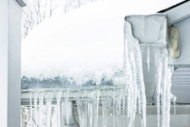 Icicles are hanging from the roof of a building.