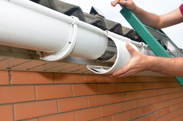 man installing new gutters on a house