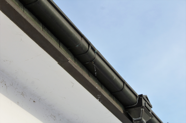 A close up of a gutter on the side of a building