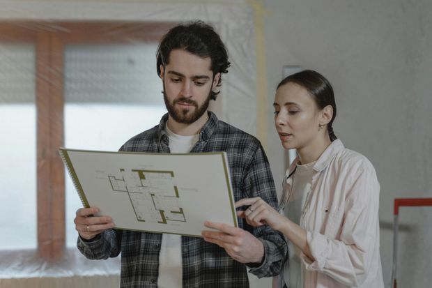 A man and a woman are looking at a house plan.