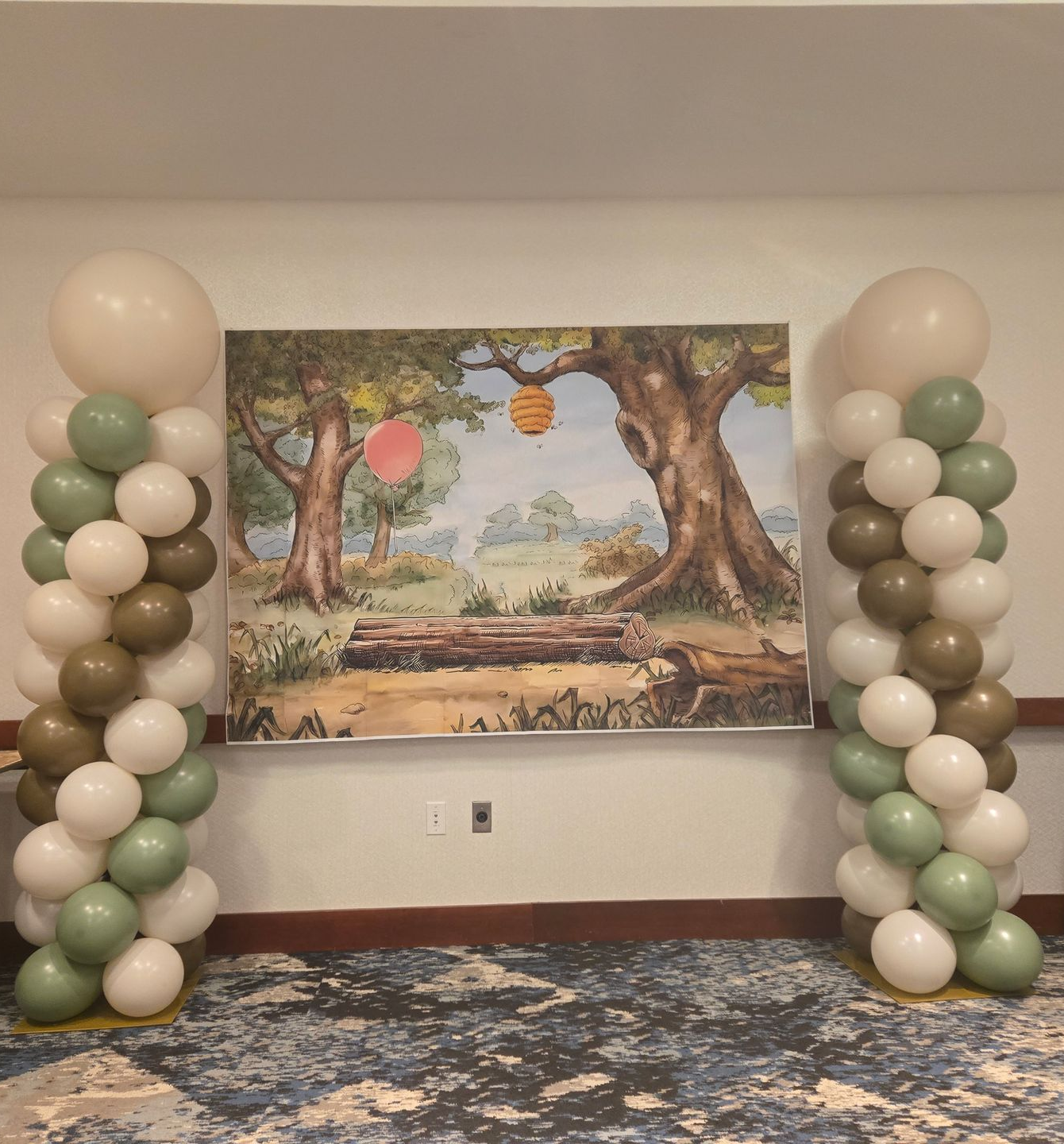 Balloon arch display framing a painted woodland mural in a decorated room