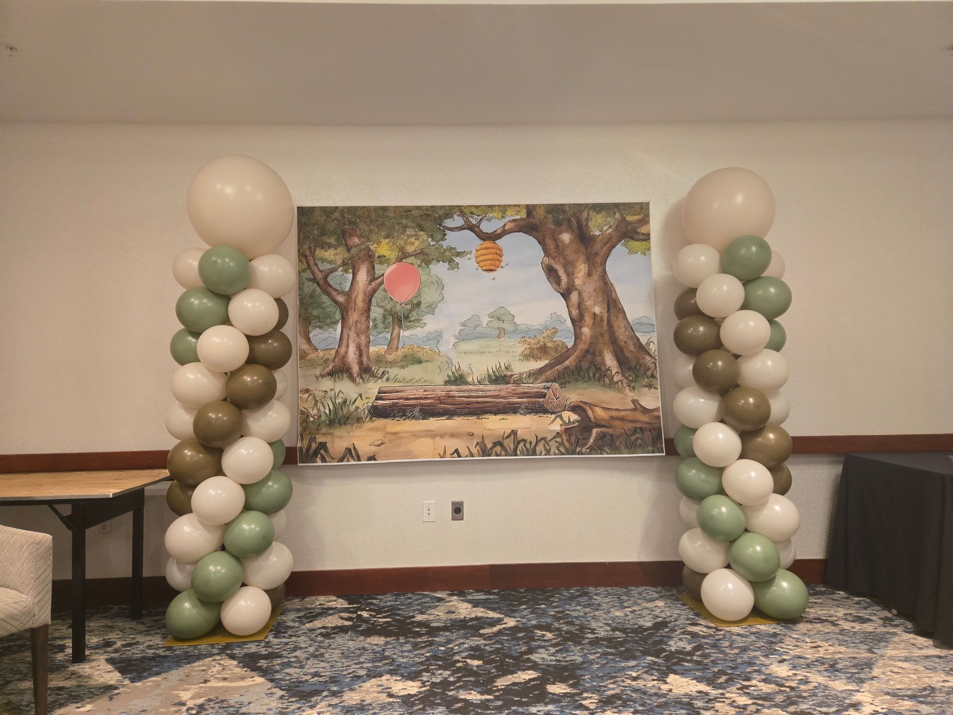 Balloon arch flanking a painted landscape backdrop in a banquet room