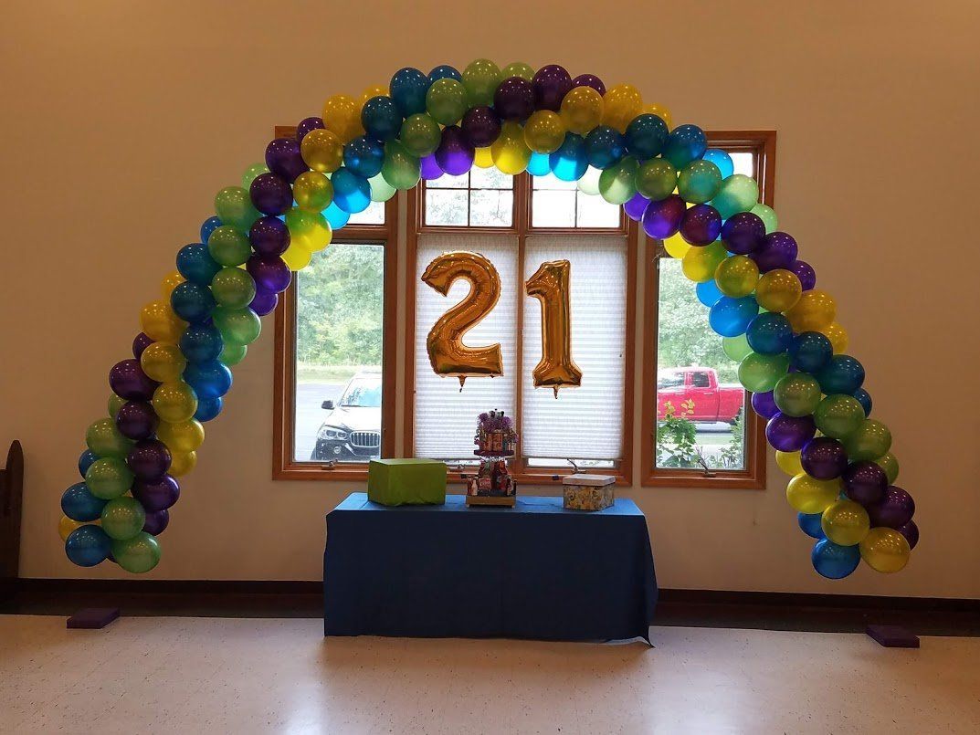 Balloon arch framing a gold “21” display in front of windows and a table
