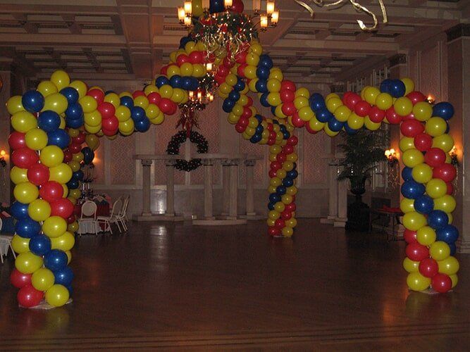 Colorful red, yellow, and blue balloon arches decorate a large indoor hall.