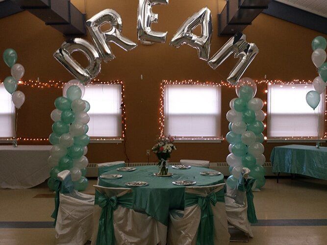 Dream-themed banquet table with silver balloons, white windows, and green-and-white decorations