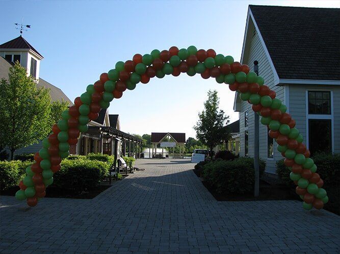 Red and green balloon arch over a residential street entrance on a sunny day