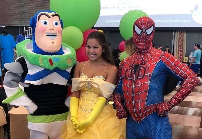 Buzz Lightyear, Belle, and Spider-Man posing together at a colorful event with balloons.