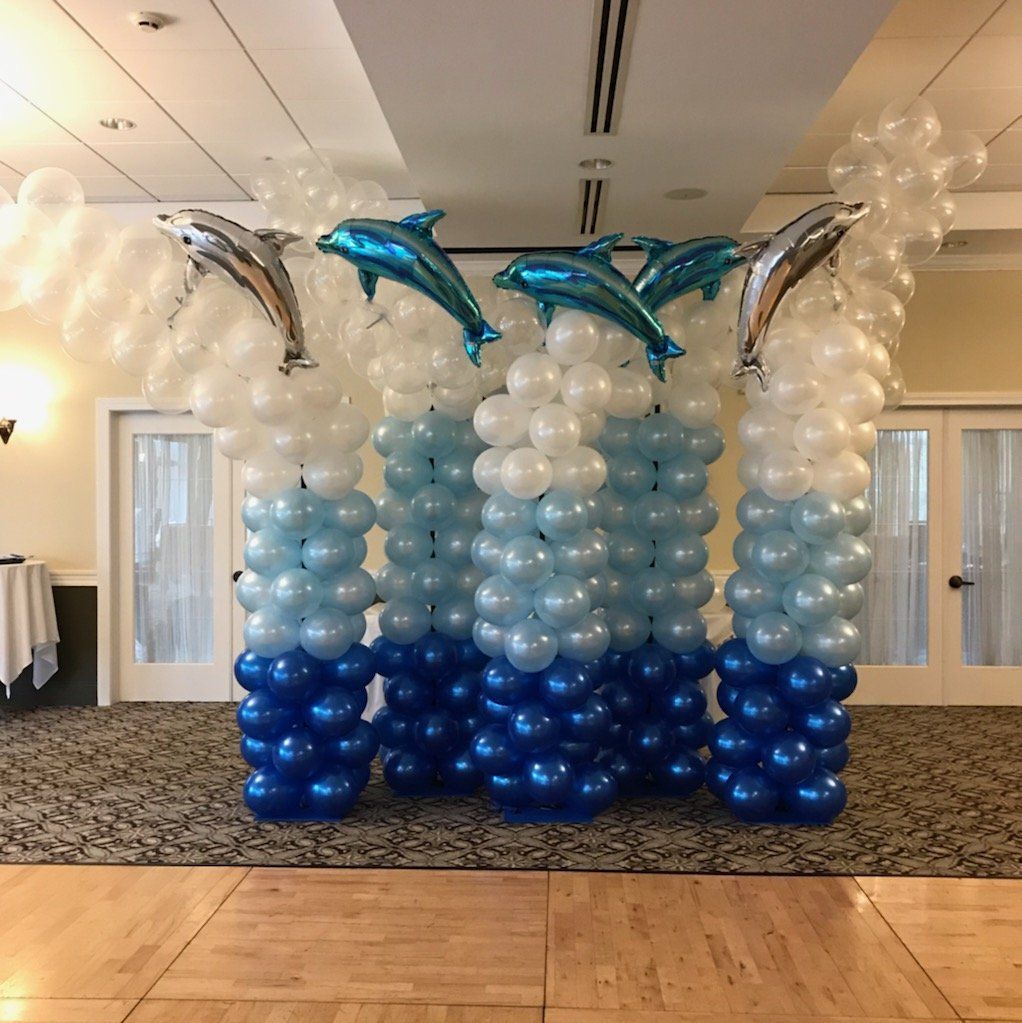 Blue and white balloon arch with dolphin balloons at an indoor event venue