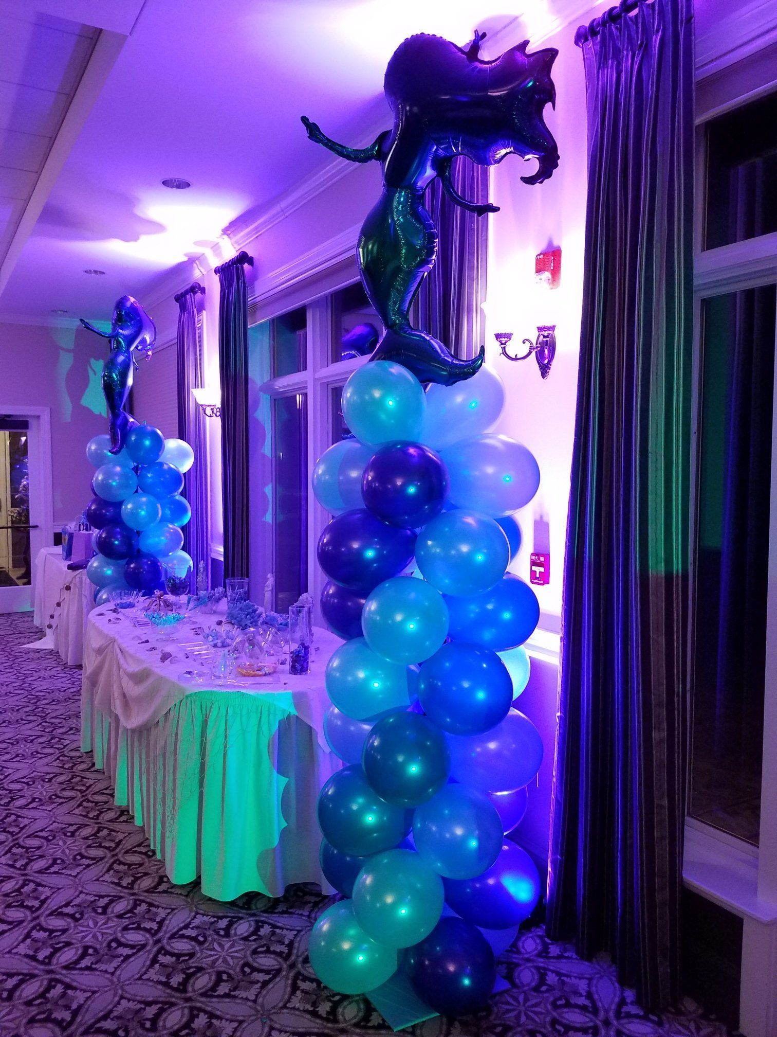 Balloon column in blue and purple beside a decorated event table in a hallway