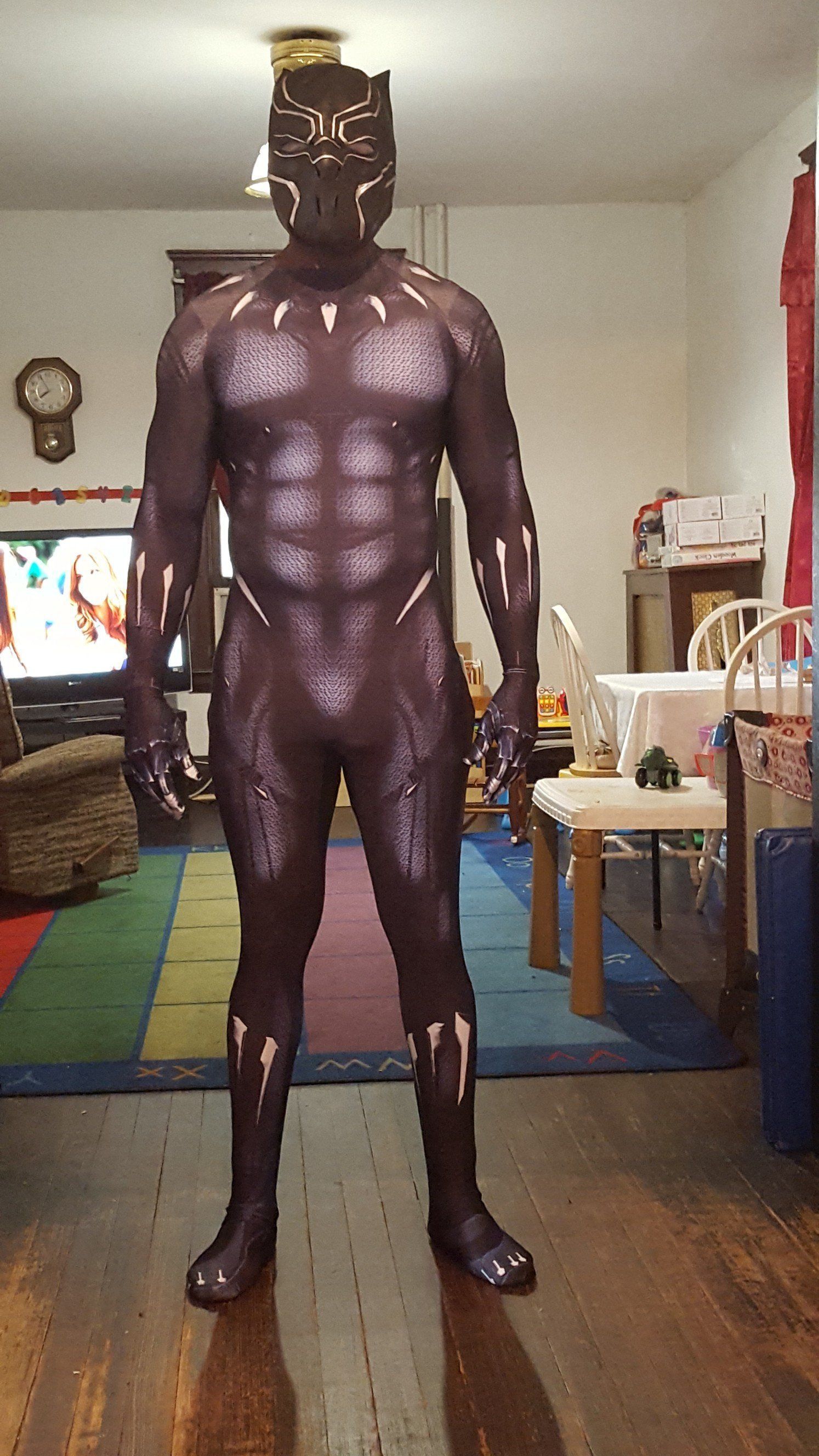 Person in a purple bodysuit and leopard-print headpiece standing indoors in a living room.