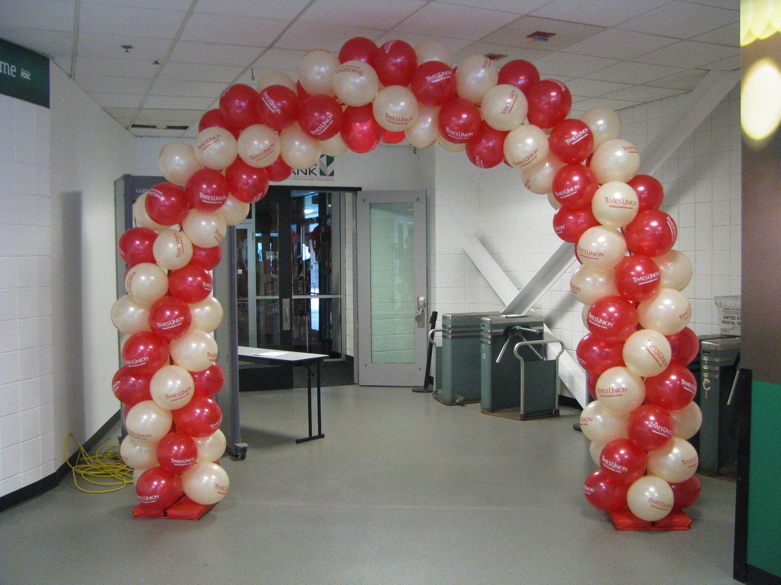 Red and white balloon arch framing an indoor hallway entrance
