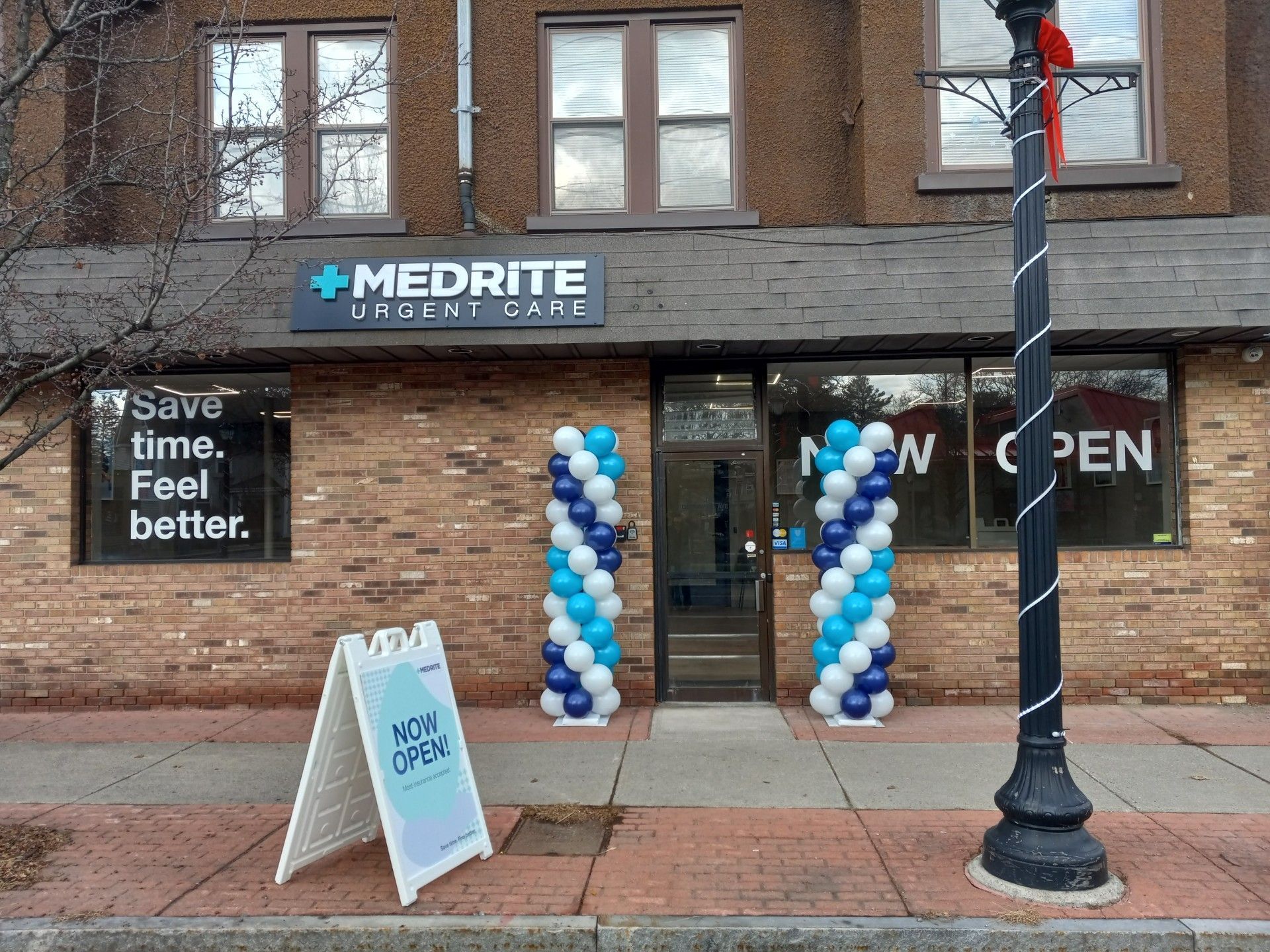 MEDRITE clinic storefront with blue-white balloon columns and “Now Open” signs on the windows
