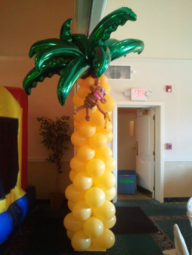 Balloon palm tree decoration with yellow trunk and green leaves in an indoor room.