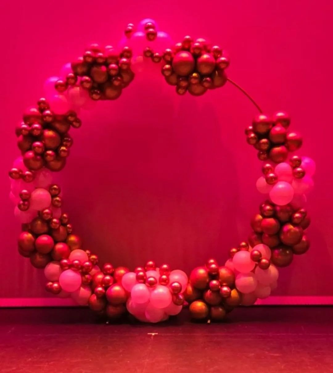 Pink and gold balloon wreath against a bright pink backdrop