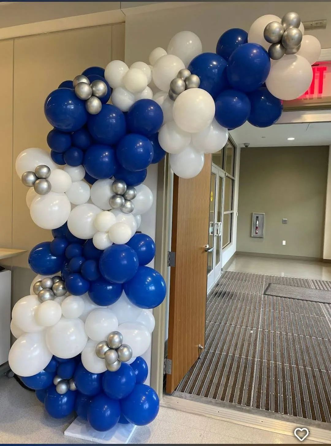 Blue, white, and silver balloon arch decorating a hallway entrance