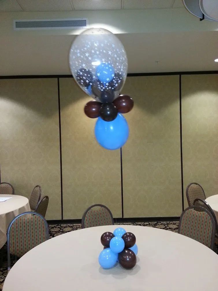 Balloon centerpiece in blue, white, and brown at a banquet table in a conference room.