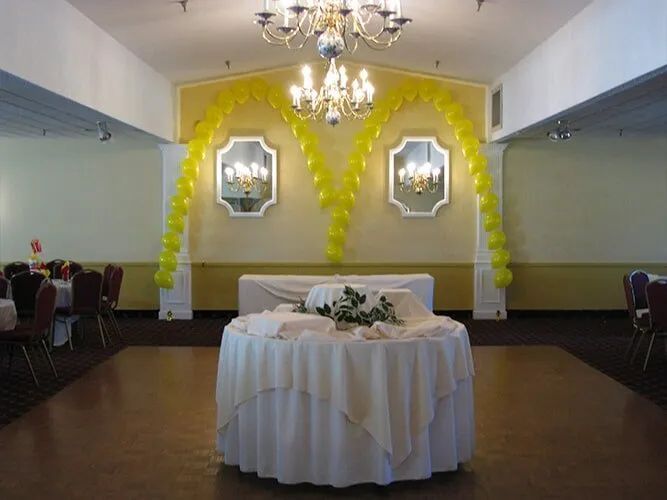 Banquet hall with yellow arch decorations, chandelier, and a round table centerpiece on the dance floor