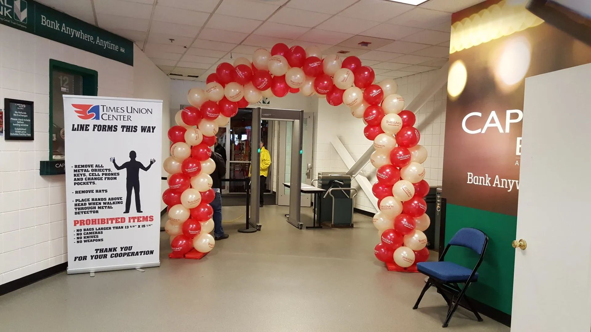 Red-and-white balloon arch at clinic entrance with sign, hallway, and blue chairs