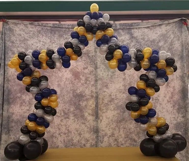 Balloon animal sculpture in blue, gold, black, and white against a marbled backdrop