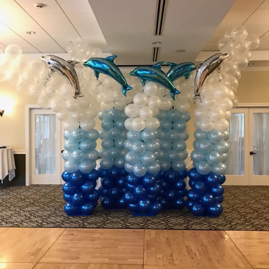 Dolphin balloon sculpture in blue, white, and silver at a banquet hall event