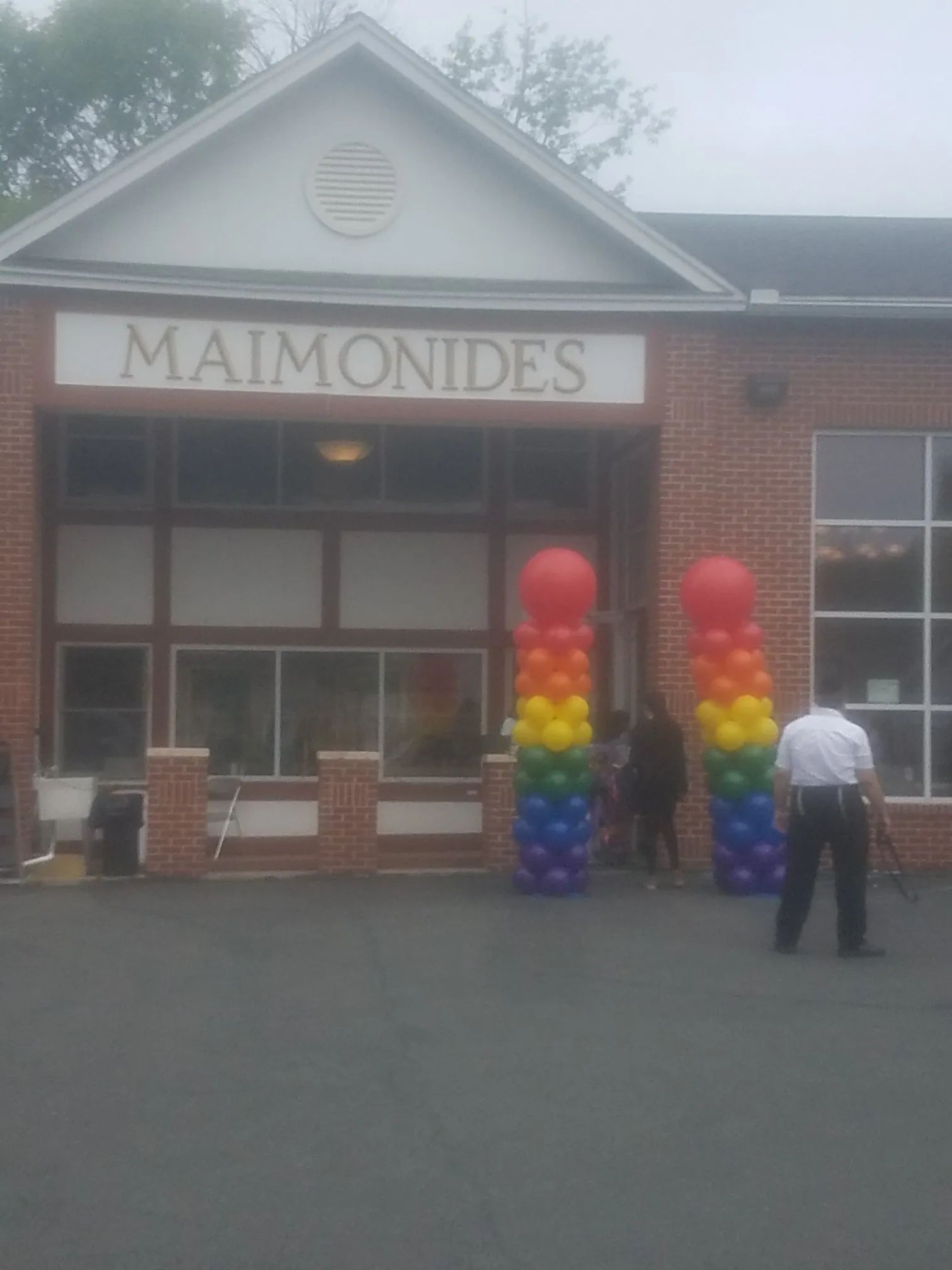 Maimonides building entrance with rainbow balloon columns and a person standing nearby
