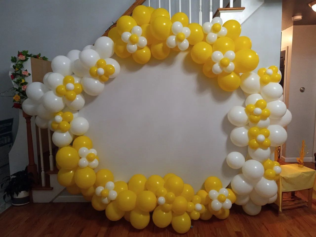 Yellow and white balloon arch framing a blank white backdrop indoors