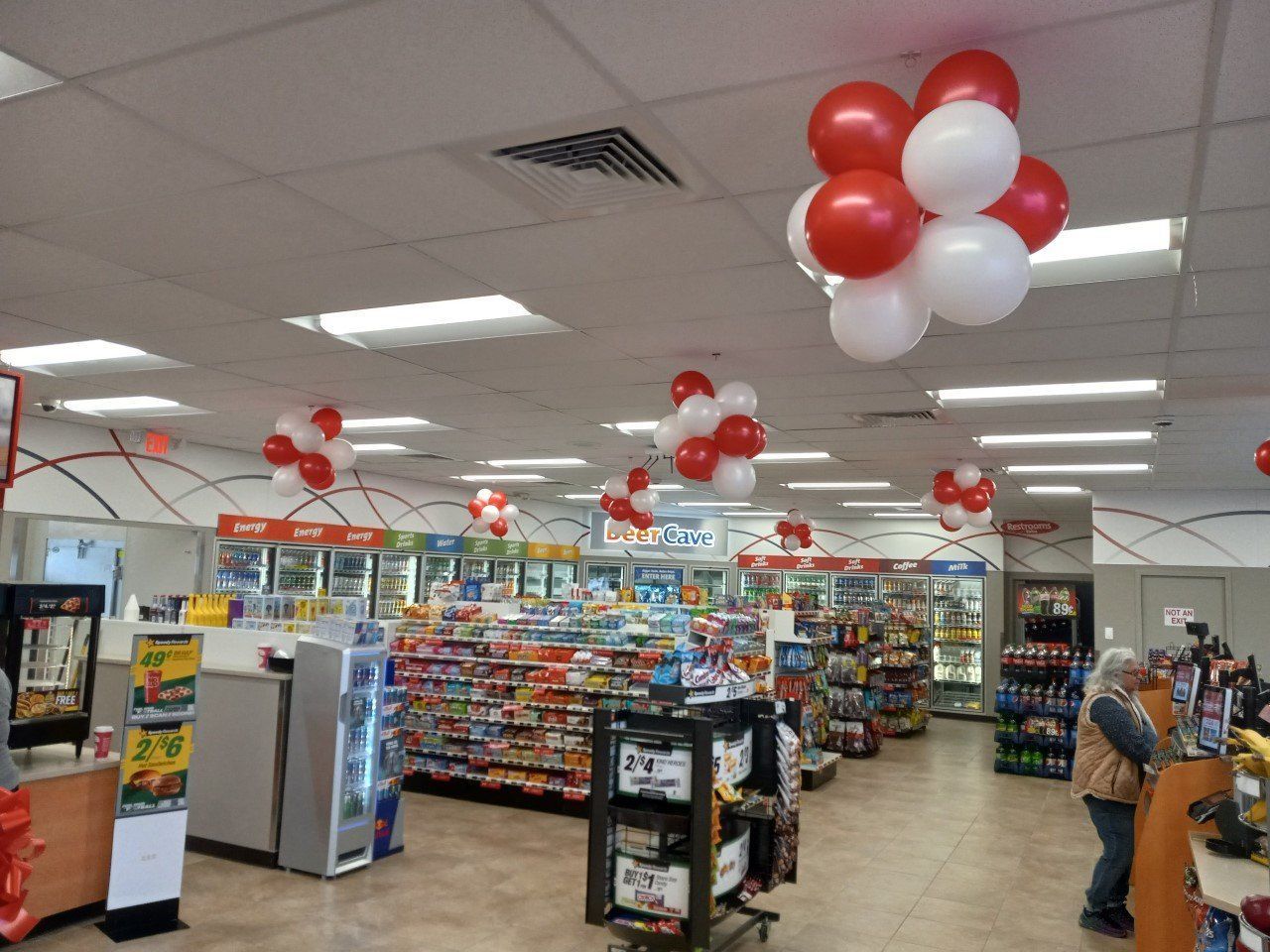 Supermarket checkout area with red and white balloons hanging from the ceiling