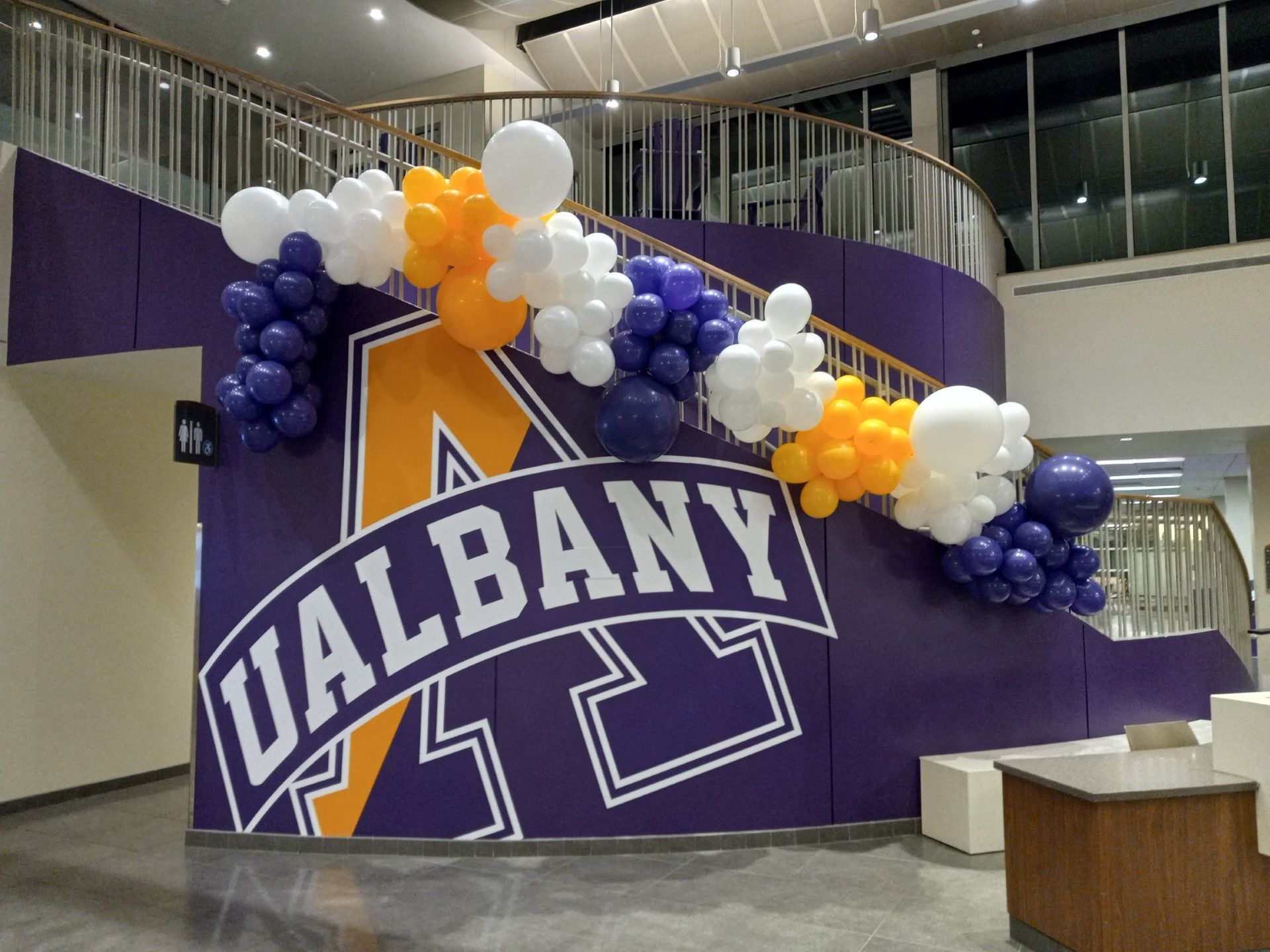 UAlbany banner with purple, white, and orange balloons in a lobby