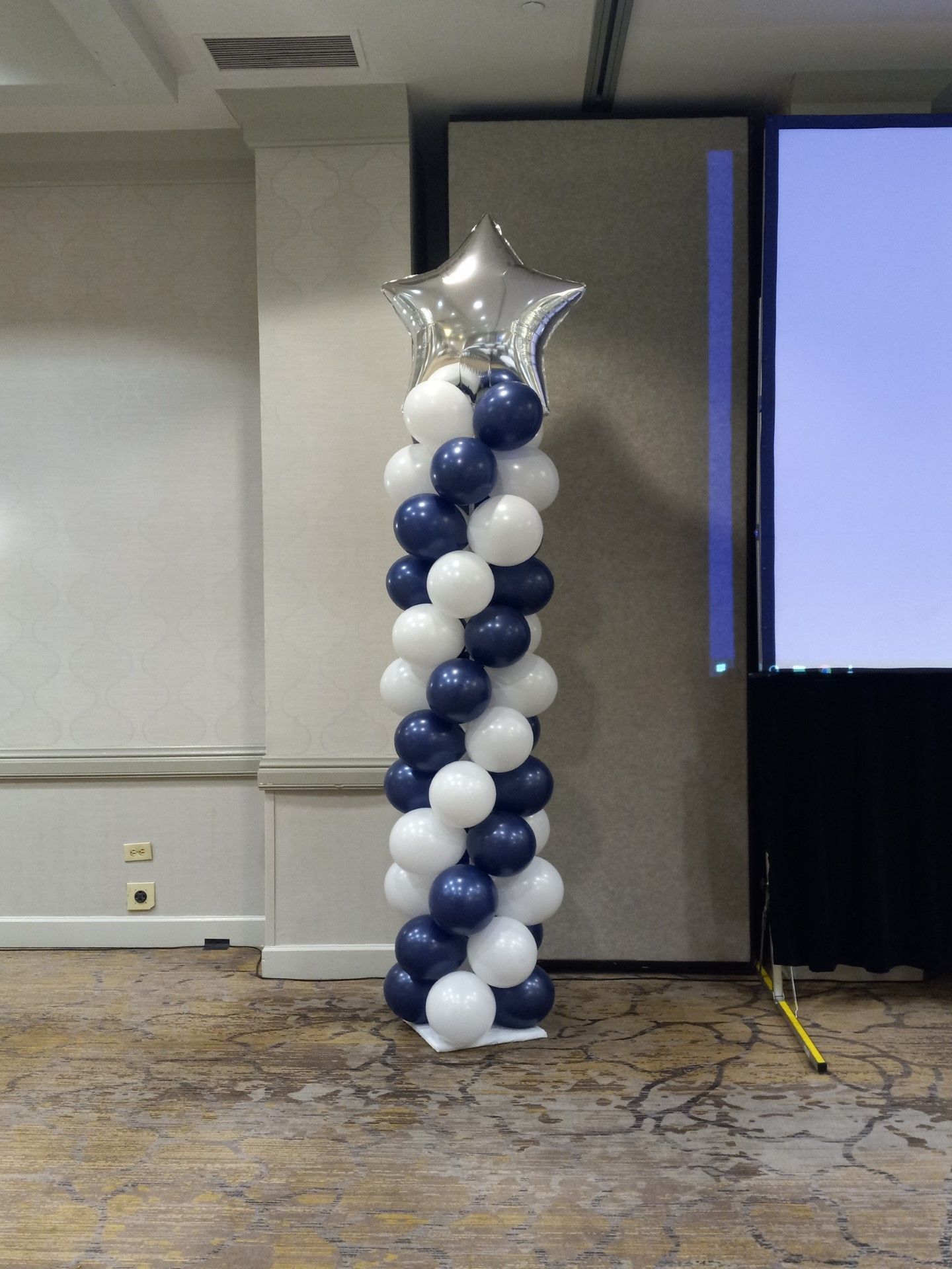 Blue and white balloon column with silver star balloon in a conference room