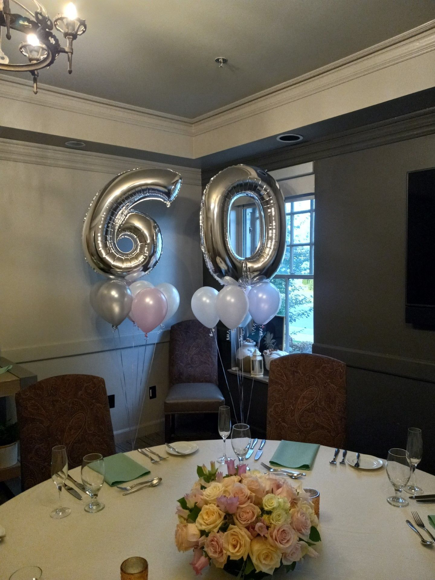 60th birthday table with gold balloons, pastel balloons, and a floral centerpiece in a dining room