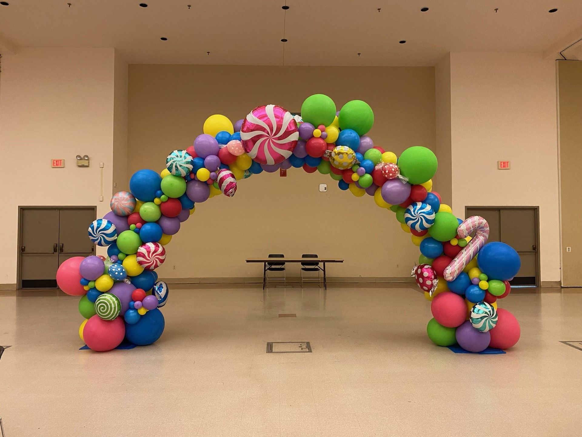 Colorful balloon arch in a large hall, with bright balloons arranged over a central opening.