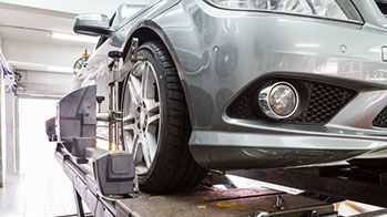 A car is being aligned on a lift in a garage.