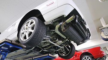 A white car is being lifted on a lift in a garage.