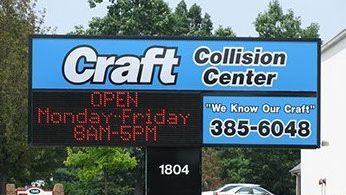 A sign for craft collision center is displayed in front of a building.