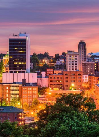 An aerial view of a city at night with a sunset in the background.