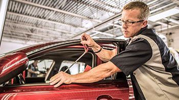 A man is working on a red car in a garage.