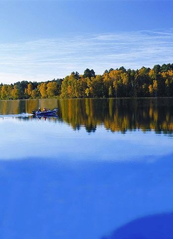 A lake with trees on the shore and boats in the water