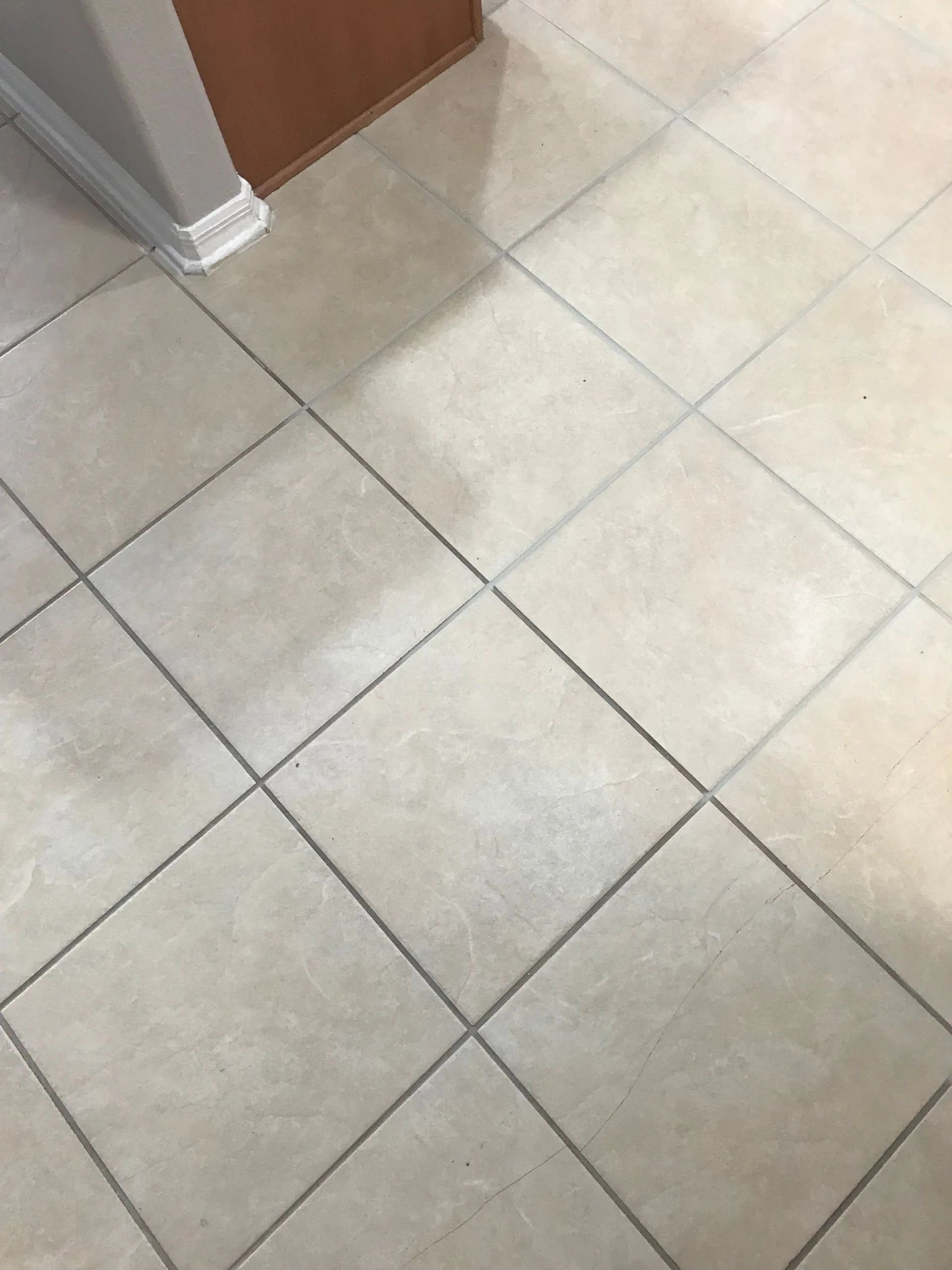 Light beige tiled floor with a wall corner and doorway trim.
