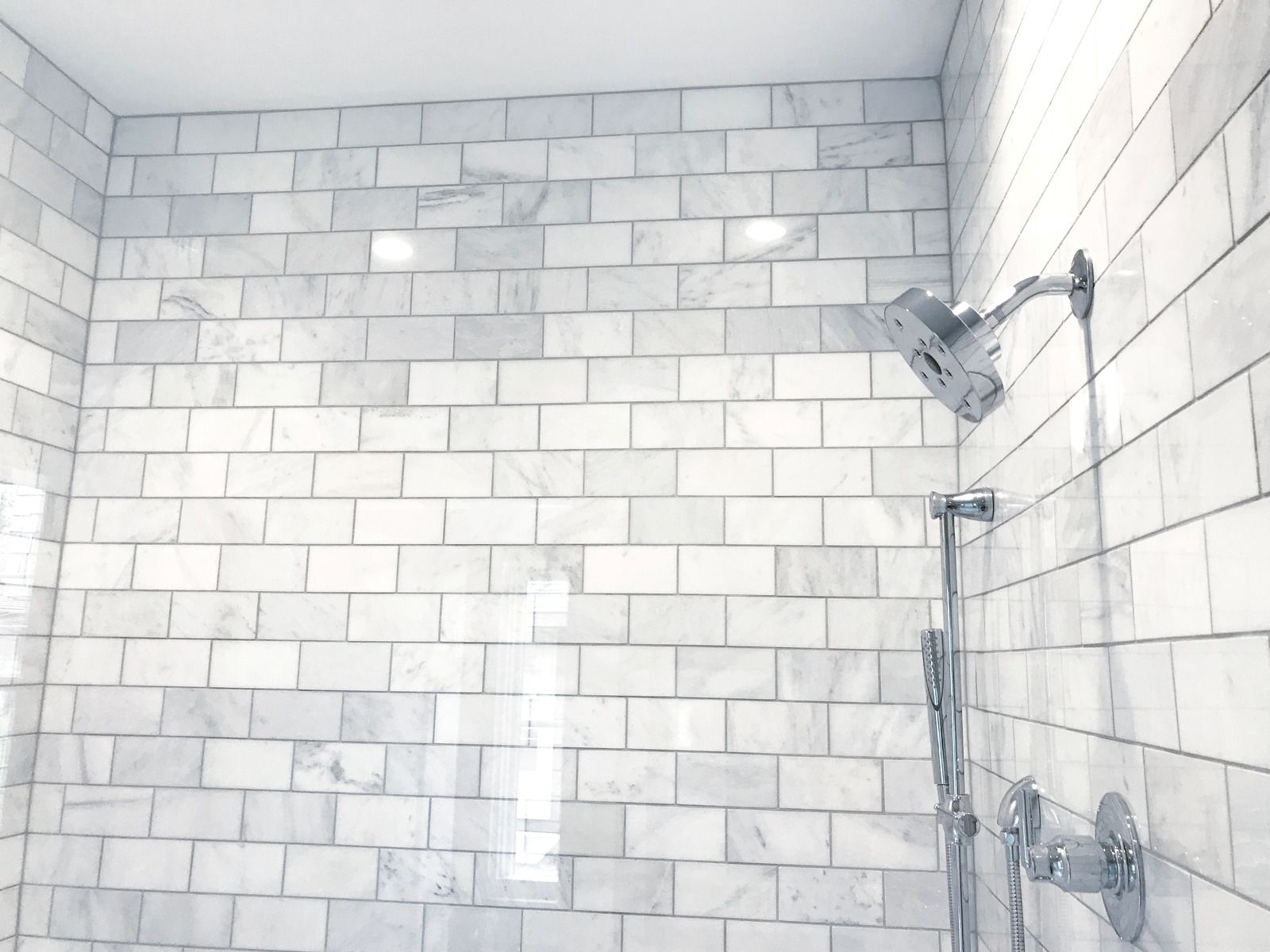 White marble-tiled shower with chrome showerhead and fixtures.